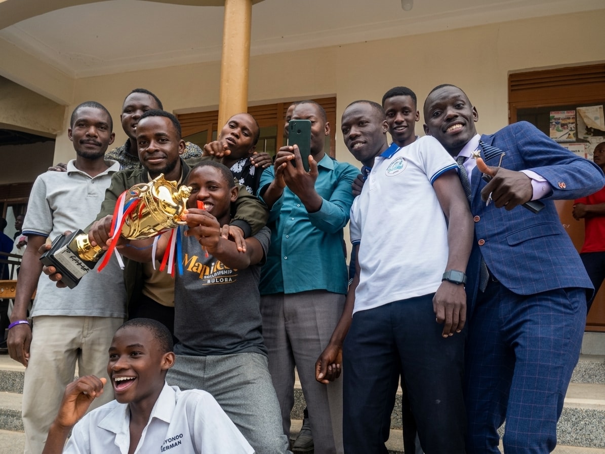 Buloba Christian High School students and staff celebrating together around a gold trophy