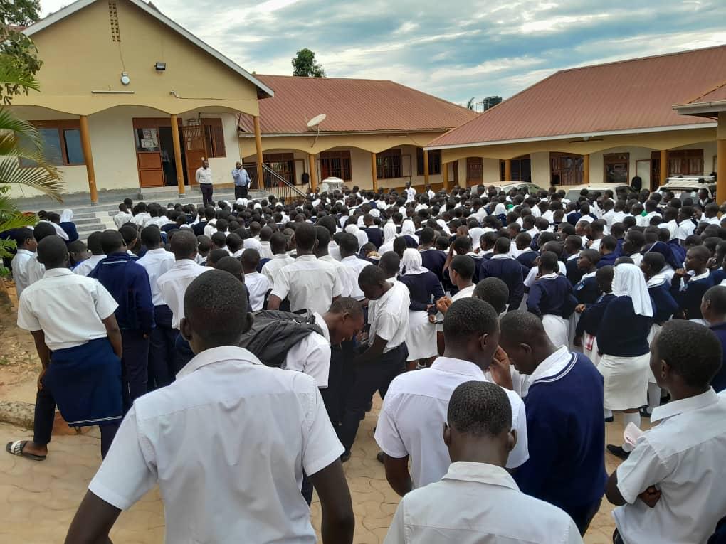 Morning assembly at Buloba Christian High School, students in white and navy uniform facing teachers on the steps